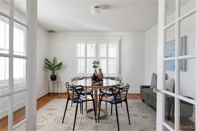 dining room featuring baseboards, a healthy amount of sunlight, and wood finished floors