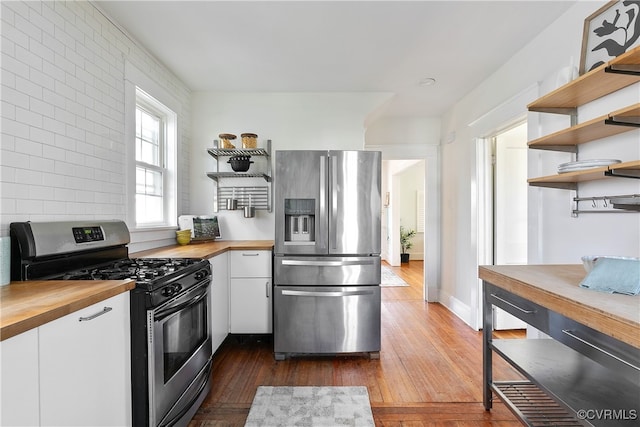 kitchen with wooden counters, appliances with stainless steel finishes, white cabinetry, and open shelves