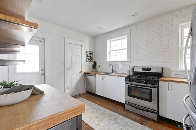 kitchen featuring backsplash, a healthy amount of sunlight, stainless steel appliances, wood counters, and a sink