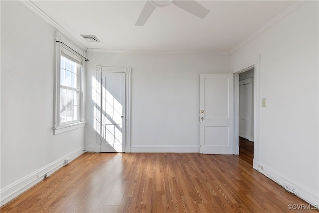 spare room featuring visible vents, baseboards, crown molding, and light wood finished floors