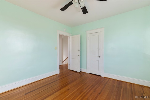 empty room with baseboards, wood-type flooring, and a ceiling fan