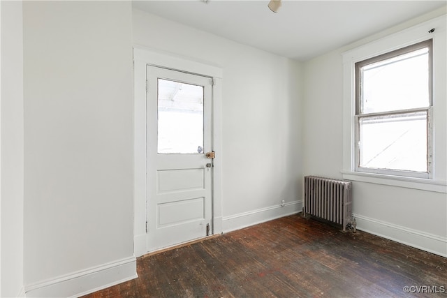 doorway with baseboards, hardwood / wood-style floors, and radiator heating unit