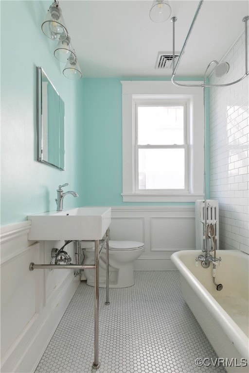 bathroom with visible vents, toilet, wainscoting, and a freestanding bath