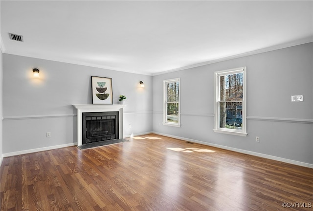 unfurnished living room with visible vents, wood finished floors, a fireplace, crown molding, and baseboards