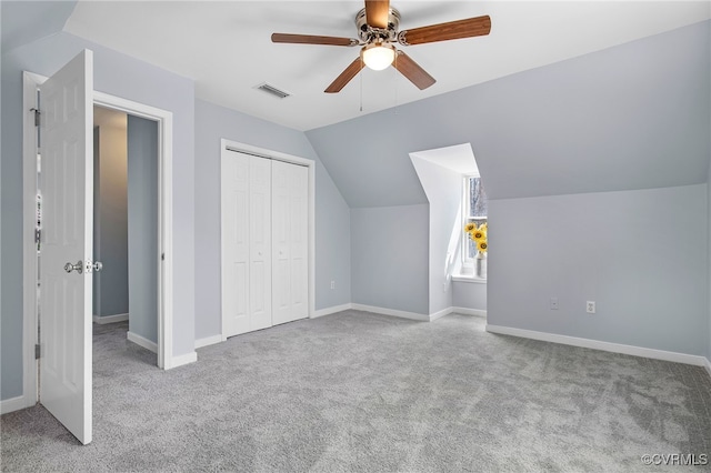 additional living space featuring visible vents, a ceiling fan, carpet flooring, baseboards, and vaulted ceiling