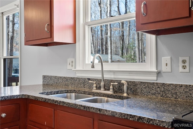 kitchen with dark countertops, plenty of natural light, brown cabinetry, and a sink