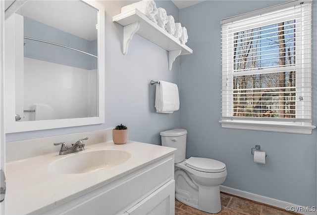 bathroom with baseboards, toilet, walk in shower, and vanity