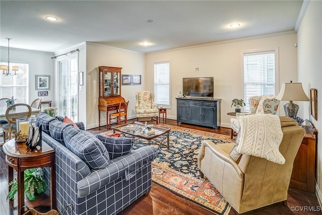 living room featuring dark wood-type flooring, a notable chandelier, baseboards, and ornamental molding