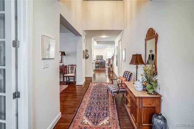 hall with dark wood finished floors, stairway, and baseboards