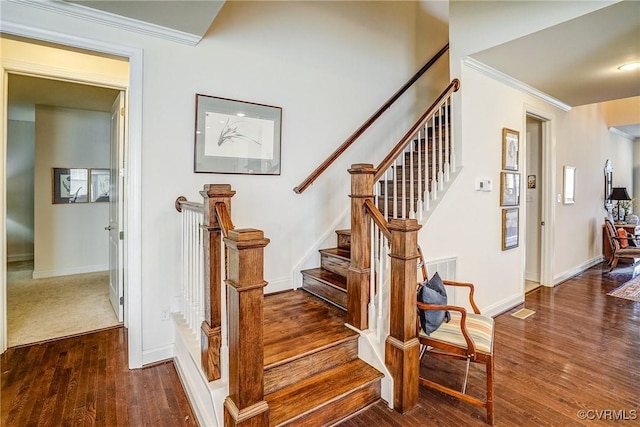 staircase featuring crown molding, wood finished floors, and baseboards