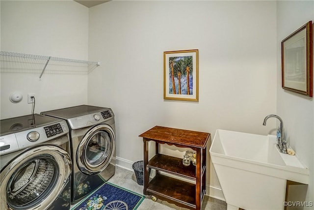 washroom featuring a sink, laundry area, baseboards, and washer and clothes dryer