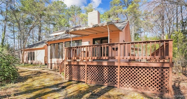 rear view of house with a wooden deck and a chimney