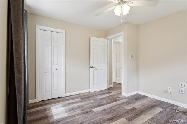 unfurnished bedroom with wood finished floors, baseboards, a closet, and ceiling fan