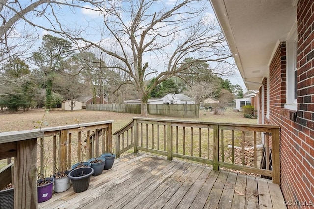 deck featuring a storage unit, an outbuilding, and a fenced backyard