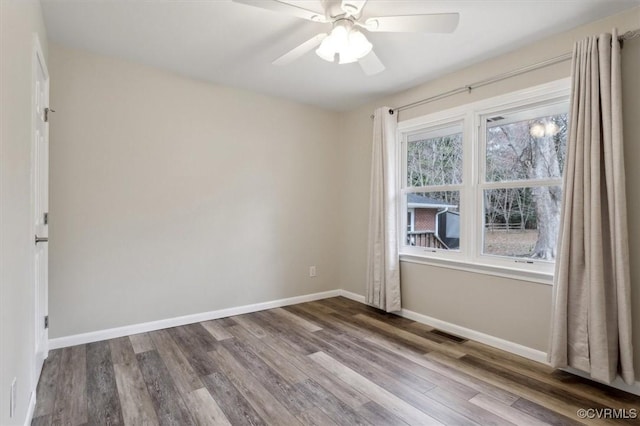 empty room featuring ceiling fan, wood finished floors, visible vents, and baseboards