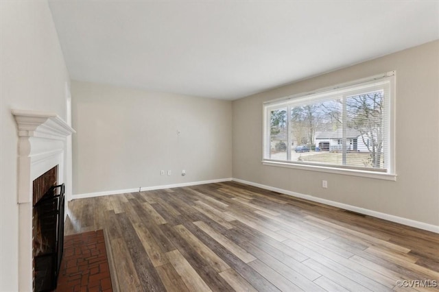 unfurnished living room with wood finished floors, a fireplace, visible vents, and baseboards