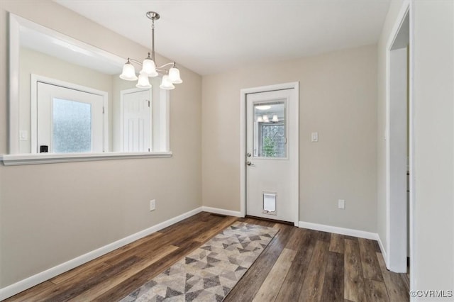 foyer entrance with a notable chandelier, baseboards, and wood finished floors