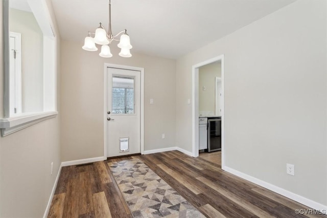 foyer entrance with beverage cooler, a chandelier, baseboards, and wood finished floors