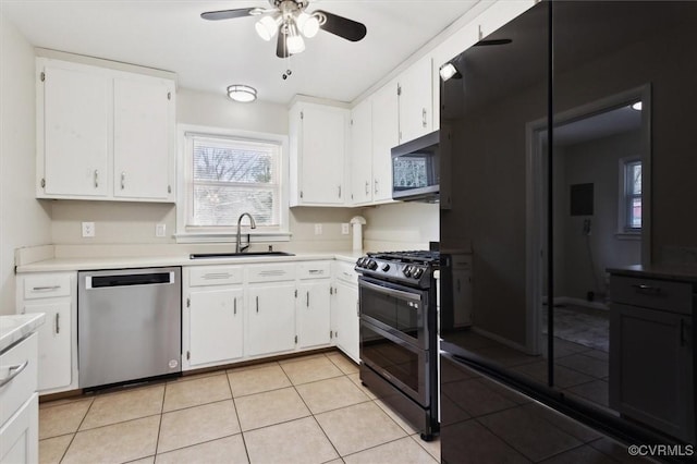 kitchen featuring light tile patterned floors, a sink, stainless steel appliances, light countertops, and white cabinetry