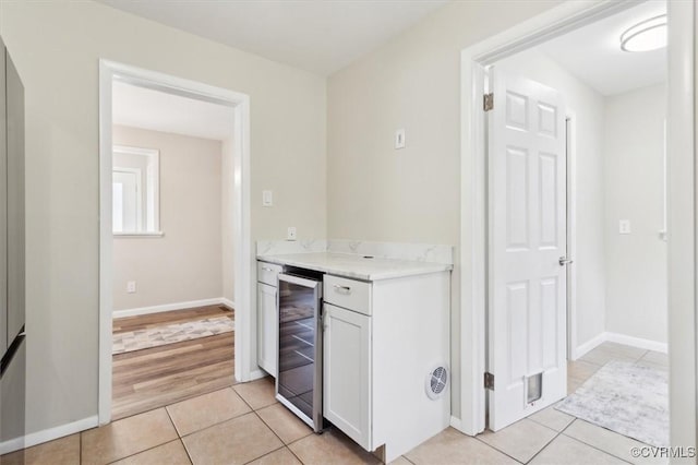 kitchen featuring light countertops, wine cooler, light tile patterned flooring, and white cabinets