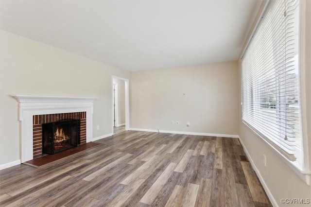 unfurnished living room with a fireplace, baseboards, and wood finished floors