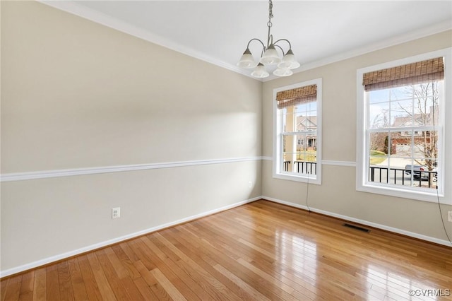 spare room featuring hardwood / wood-style floors, crown molding, a notable chandelier, and visible vents