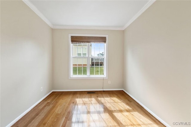 empty room featuring light wood-type flooring, baseboards, visible vents, and crown molding