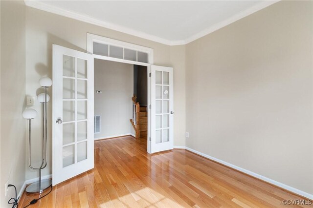 unfurnished room with visible vents, crown molding, baseboards, light wood-style flooring, and french doors