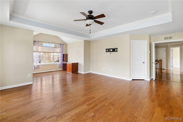 unfurnished living room with a raised ceiling, wood finished floors, baseboards, and ceiling fan