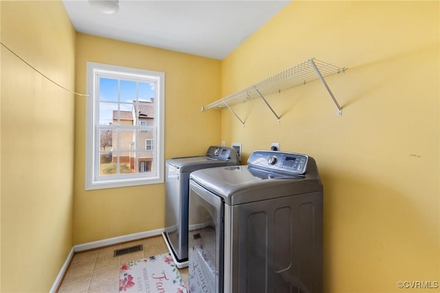 washroom featuring visible vents, baseboards, washing machine and dryer, laundry area, and light tile patterned flooring