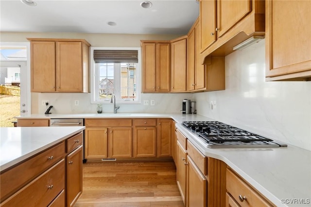 kitchen featuring stainless steel gas cooktop, light wood-type flooring, light countertops, and a sink