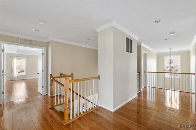 hallway featuring hardwood / wood-style floors, an upstairs landing, visible vents, and a wealth of natural light