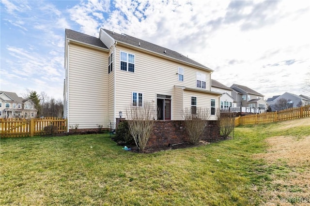 rear view of property featuring a lawn and fence