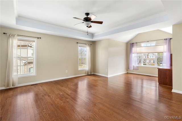 empty room with baseboards, a raised ceiling, a ceiling fan, and wood finished floors