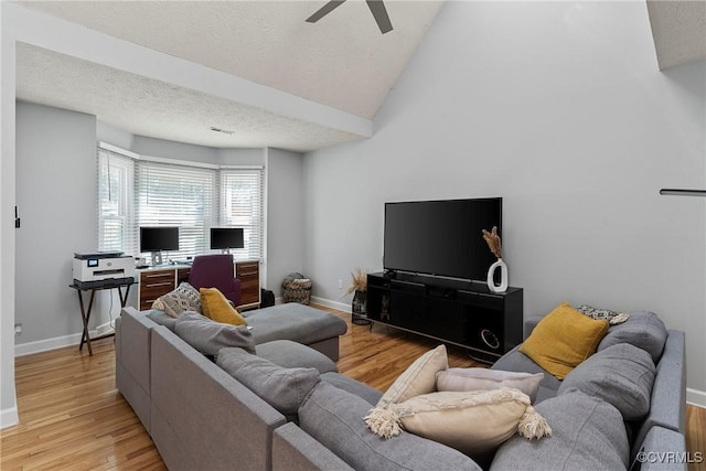 living area with lofted ceiling, light wood-style flooring, baseboards, and a textured ceiling