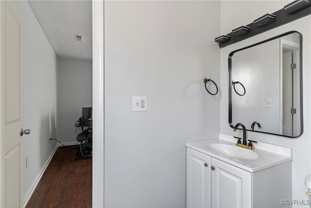 bathroom featuring visible vents, vanity, baseboards, and wood finished floors