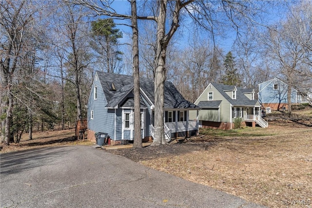 view of front facade featuring a porch, driveway, and roof with shingles