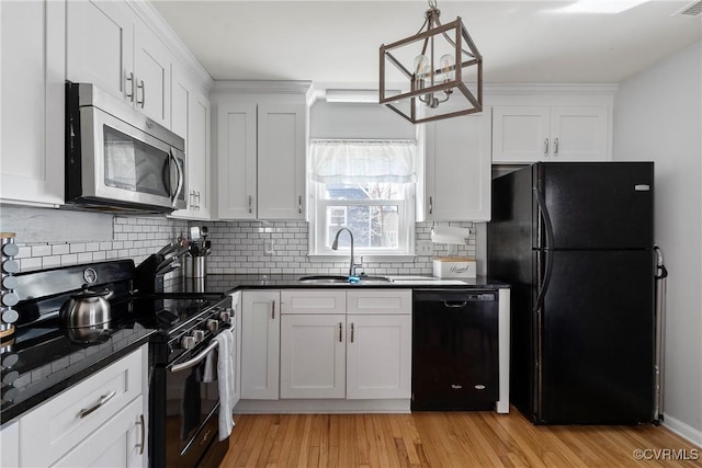 kitchen featuring a sink, black appliances, white cabinets, light wood-style floors, and dark countertops