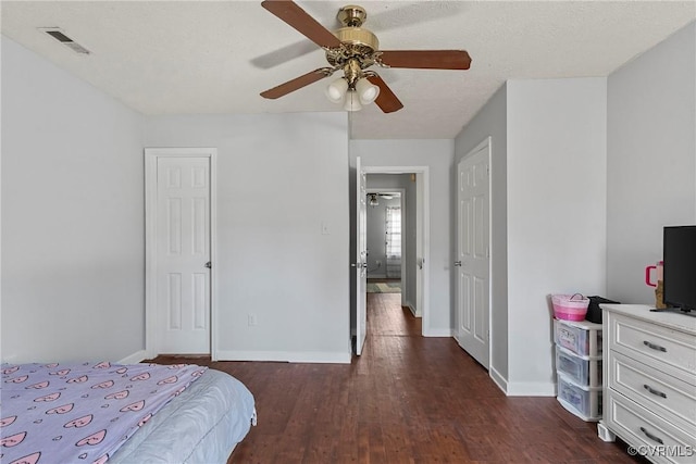 bedroom with a ceiling fan, baseboards, visible vents, dark wood-type flooring, and a textured ceiling