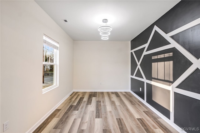 unfurnished room featuring visible vents, wood finished floors, and baseboards