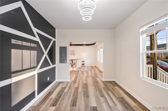 corridor featuring electric panel, baseboards, and wood finished floors