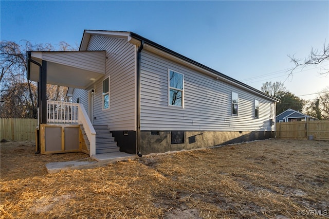 view of side of property featuring stairs, fence, and crawl space