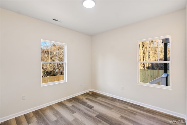 unfurnished room with visible vents, baseboards, and wood finished floors