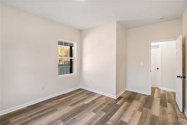 spare room featuring baseboards and wood finished floors