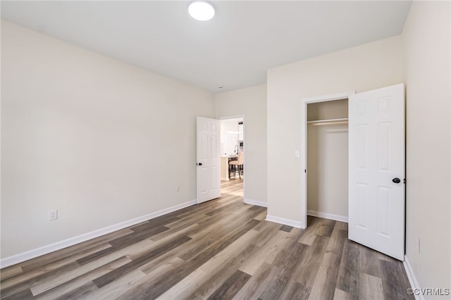 unfurnished bedroom featuring a closet, baseboards, and wood finished floors