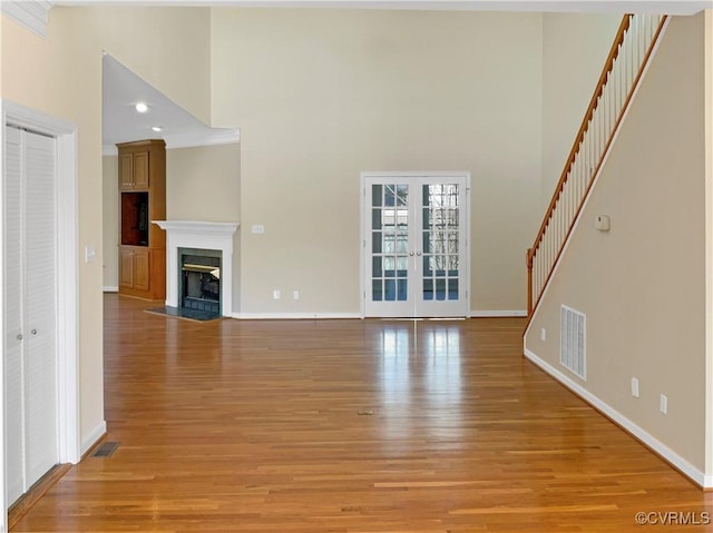 unfurnished living room featuring light wood-style floors, a fireplace with flush hearth, french doors, and visible vents