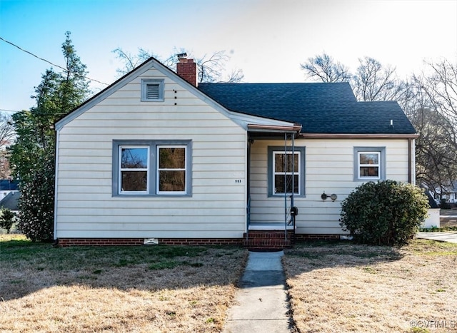 bungalow with a front yard, a chimney, and a shingled roof