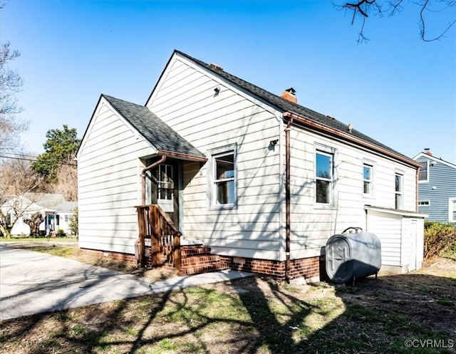 back of house featuring a shingled roof and heating fuel