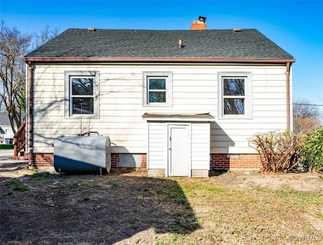 back of property with a chimney, heating fuel, and roof with shingles