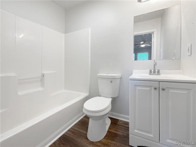 full bath featuring vanity, wood finished floors, baseboards,  shower combination, and toilet